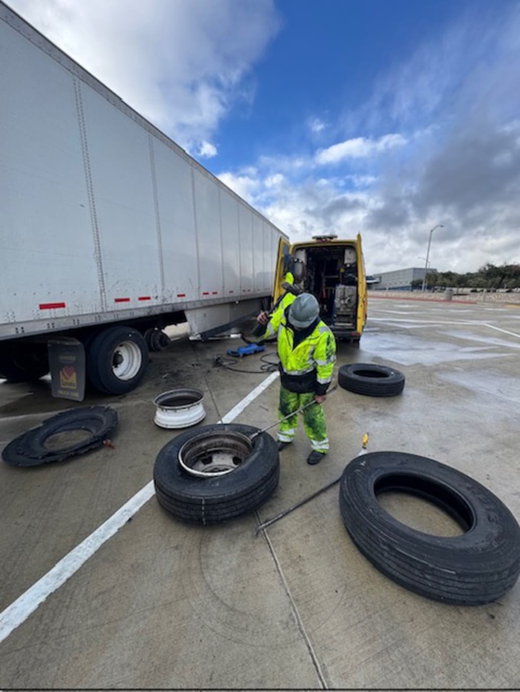 A&T technician changing a commercial trailer tire beside an open yellow service van